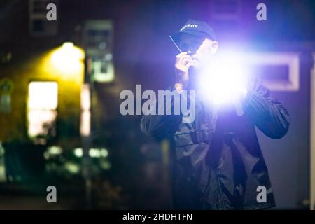 Security Guard Officer Using Walkie-Talkie Radio At Night Stock Photo