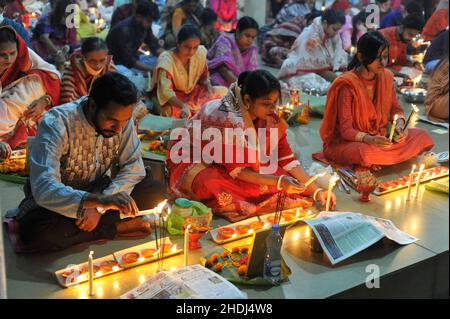Devotees offer prayers during the ritual called Kartik Brati or Rakher Upobash with the lighting of oil lamps and candles, at the Lokonath Temple of Korer Para, during the religious festival of the 18th Century Hindu saint and philosopher in Bengal LOKANATH. Sylhet, Bangladesh. Stock Photo