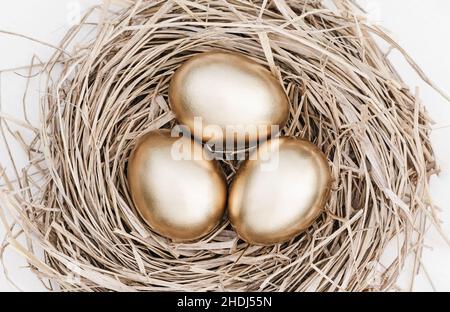 Golden eggs in nest, closeup view from above, light colors banner Stock Photo