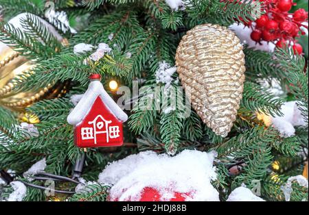 Red Christmas small hut and golden pine cone on the Christmas tree. Stock Photo