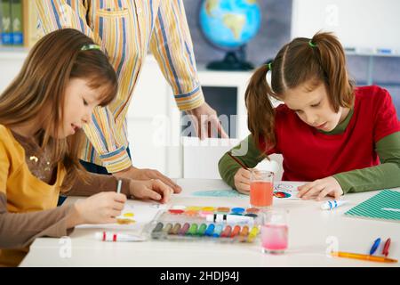 Side view of schoolgirl drawing on book at desk in classroom of ...