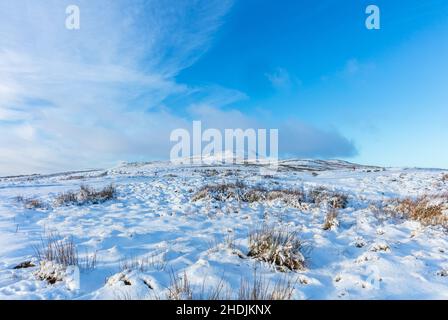 Penhill in Winter covered in snow with blue sky background.  Penhill is 1,726 ft high and a prominent feature above the village of West Witton in the