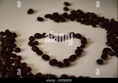 A heart laid from roasted coffee beans on white background Stock Photo