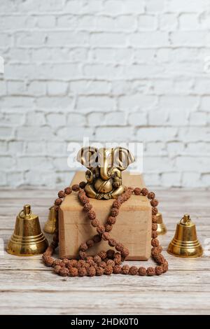 Bronze statue of Lord Ganesha, hindu God of success. Rudraksha rosary for meditation on bright wooden background and yoga brick. Stock Photo