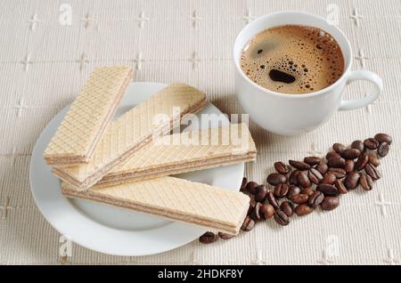 Wafers with chocolate in white plate and cup of coffee is located on a napkin Stock Photo