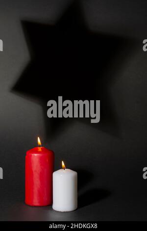 Two burning candles and shadow of David star in the background. International Holocaust Remembrance Day. Stock Photo