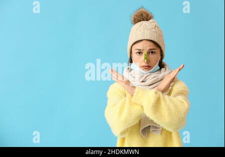 Ill young woman with clothespin on her nose against color background Stock Photo