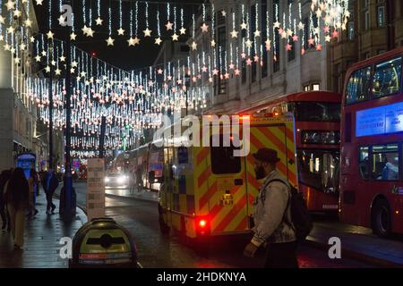 London, UK. 6th Jan, 2021. an ambulance drives along Oxford Street with it's emergency lights on, with the Christmas lights on in the background. Credit: Anna Watson/Alamy Live News Stock Photo