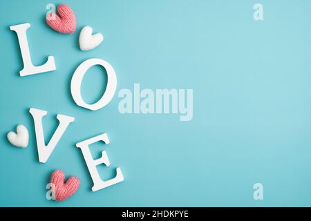 Happy Valentines Day concept. Word Love and knitted hearts on pastel blue background. Flat lay, top view, copy space. Stock Photo