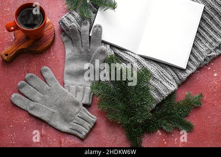 Warm gloves, cup of tea and blank book on red background Stock Photo