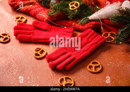 Warm gloves and Christmas lights on red background Stock Photo