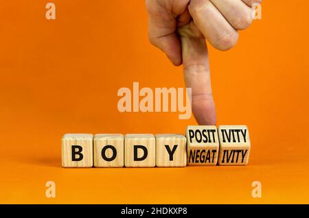 Body positivity or negativity symbol. Psychologist turns cubes, changes words body negativity to body positivity. Orange background, copy space. Psych Stock Photo