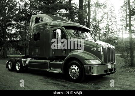 Shiny Peterbilt semi truck with the setting sun the distance done with a green filter. Stock Photo