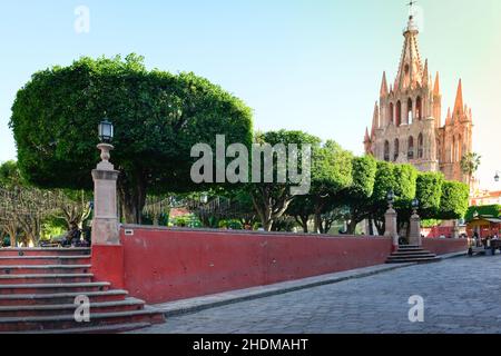 The Neo-gothic pink Parroquia Church of St. Miguel the Archangel, overlooks the well manicured El Jardin, the garden in San Miguel de Allende, Mexico Stock Photo