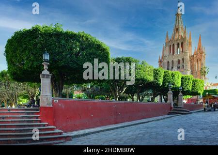 The Neo-gothic pink Parroquia Church of St. Miguel the Archangel, overlooks the well manicured El Jardin, the garden in San Miguel de Allende, Mexico Stock Photo