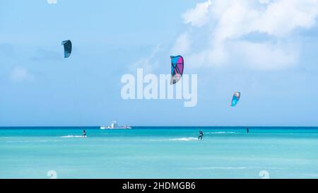 Kite boarders riding the wind on the bright turquoise Caribbean Sea waters off of Hadicurari Beach in Aruba. Stock Photo