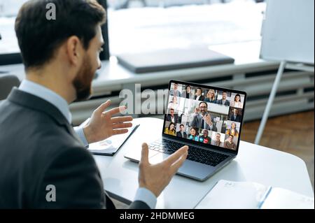 Remote business meeting. Successful man using a laptop, talking to business colleagues on a video call. Group of diverse multiracial business people on laptop screen holding video conference Stock Photo