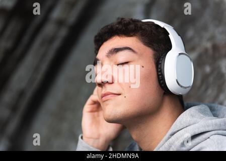 Portrait of hispanic teenager listening to music on headphones Stock Photo