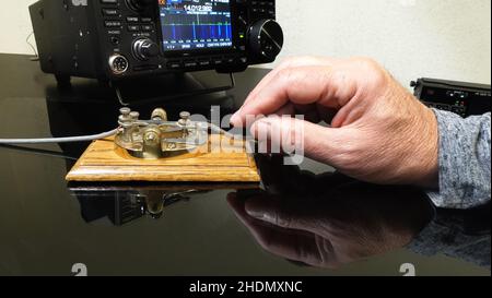 Hand tapping morse code on a telegraph straight key. Stock Photo