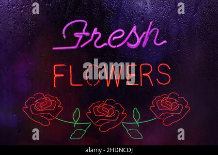 Neon Fresh Flowers Sign in Rainy Wet Window Stock Photo