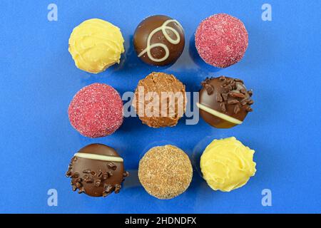 Chocolate pralines top view stock images. Chocolate candies on a blue background. Chocolate frame top view. Square-shaped chocolate pralines Stock Photo
