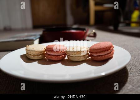 Macaroons on white plate with handbag and book in the background Stock Photo