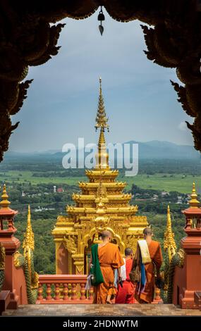 Lampang, Thailand - Sep 04, 2019 : Buddhist Monks are walking into down the gate of Wat Phra That Doi Phra Chan in Lampang. A temple on the top of a m Stock Photo