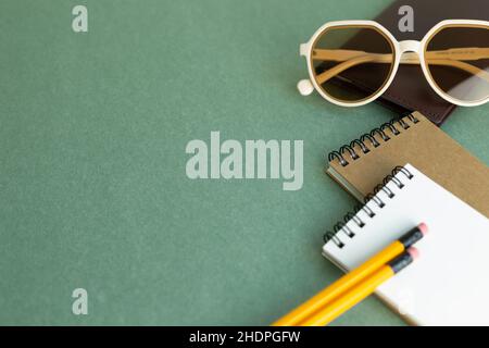 Various office supply stationery. notebook, glasses, pencil on green desk background with copy space Stock Photo