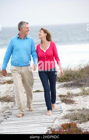 Two senior couples walking barefoot on beach Stock Photo - Alamy