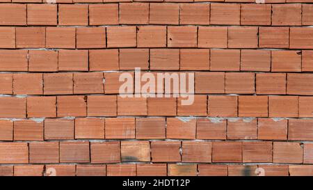 Red Brick wall background and texture. These bricks are tiled as an unfinished wall of a house under construction. Stock Photo