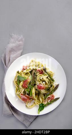 Pasta with asparagus and prosciutto on gray background. Traditional Italian Food concept. Top view, flat lay, copy space Stock Photo