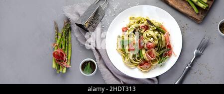 Pasta with asparagus and prosciutto on gray background. Traditional Italian Food concept. Top view, flat lay, copy space, panorama Stock Photo