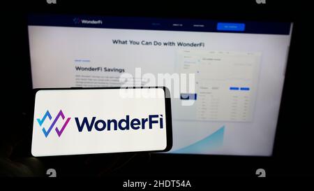 Person holding cellphone with logo of Canadian fintech company WonderFi Technologies Inc. on screen in front of webpage. Focus on phone display. Stock Photo