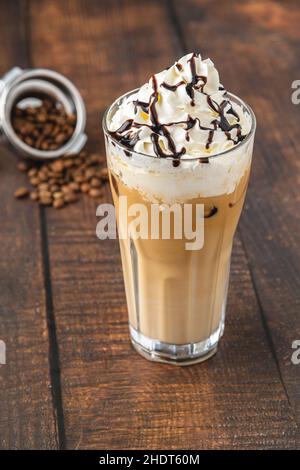 Iced coffee frappe with whipped cream in glass cup on wooden table Stock Photo