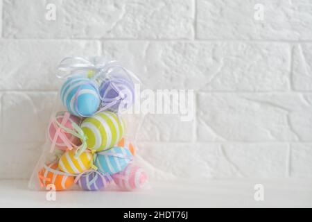 multi-colored chicken eggs in bag mesh on white background. easter Stock Photo