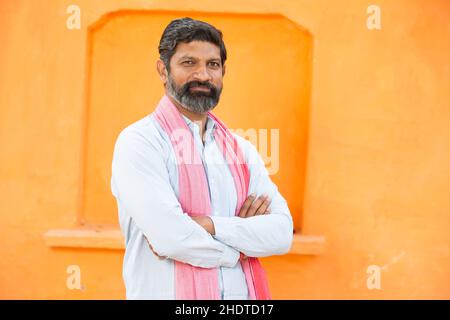 Portrait of confident indian male farmer wearing traditional kurta standing cross arm. beard man Closeup looking at camera, copy space. rural india. Stock Photo
