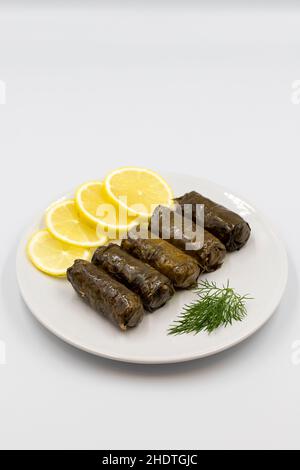 Stuffed grape leaves with olive oil on a white background. Traditional Turkish cuisine delicacies. Delicious dolma (yaprak sarma). Vertical view. Clos Stock Photo