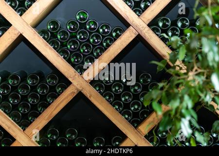 Resting wine bottles stacked on wooden racks in cellar Stock Photo