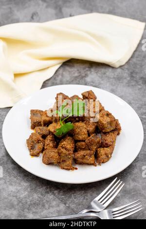 Fried liver cubes on a dark background. Turkish Traditional Food Arnavut Cigeri. Vertical view. Close up Stock Photo