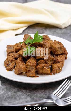 Fried liver cubes on a dark background. Turkish Traditional Food Arnavut Cigeri. Vertical view. Close up Stock Photo