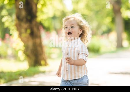 Cute little boy with curly blonde hair playing in park Stock Photo