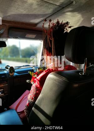 Vertical closeup of the woman sitting on the front seat wearing a red dress with head decoration. Stock Photo