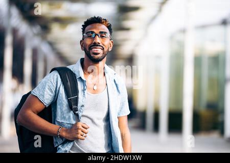 Portrait of smiling black male student with glasses and backpack Stock Photo