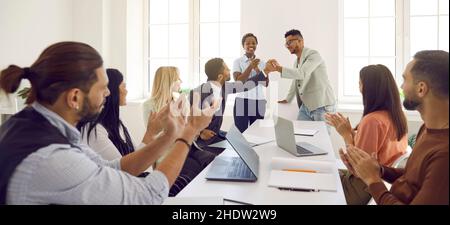 Diverse employees congratulate man on business achievements, excellent work results or promotion. Stock Photo