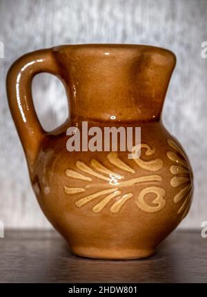 A small brown clay jug close-up on the table. Stock Photo