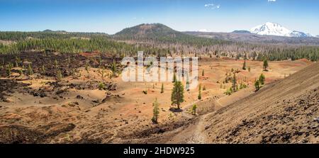 Volcanic landscape with red, orange ashes in Painted Dunes in Lassen National Forest. From cinder cone in July. Lassen peak with snow at the backgroun Stock Photo