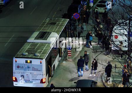 Thessaloniki, Greece car accident on a main city road at night. Elevated view of OASTH public transport bus having crashed onto parked vehicles, with passengers having just got out. Stock Photo