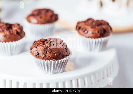 Close up of chocolate muffin or cupcake on bright white background with other cupcakes in blurry background Stock Photo