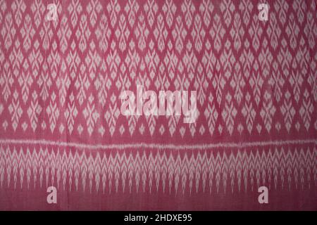 Pink color hand woven cotton fabric in Thai ancient style pattern. Top view for background or wallpaper Stock Photo