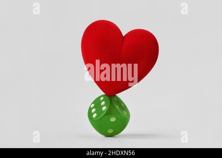 Heart standing balanced on green dice - Concept of love and risk Stock Photo